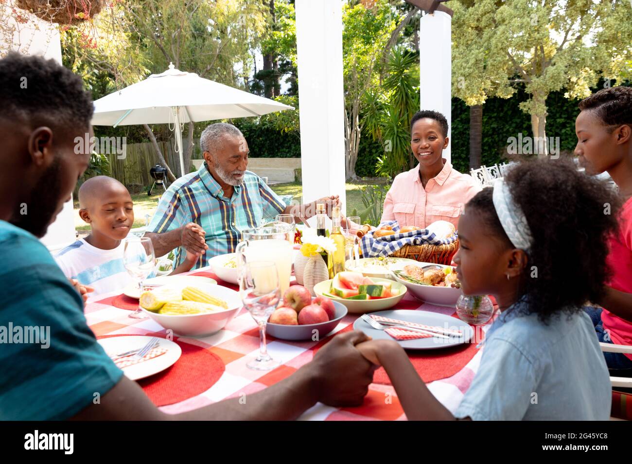 Coppia africana americana anziana e la loro famiglia seduti accanto ad un tavolo in giardino Foto Stock