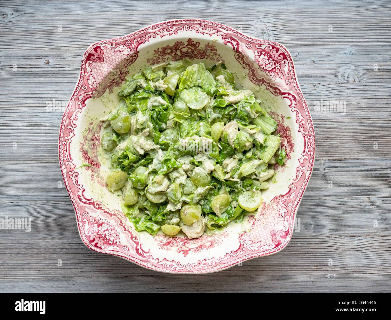 vista dall'alto di insalata con uva, dragoncello e pollo in ciotola ornamentale su tavolo di legno grigio Foto Stock