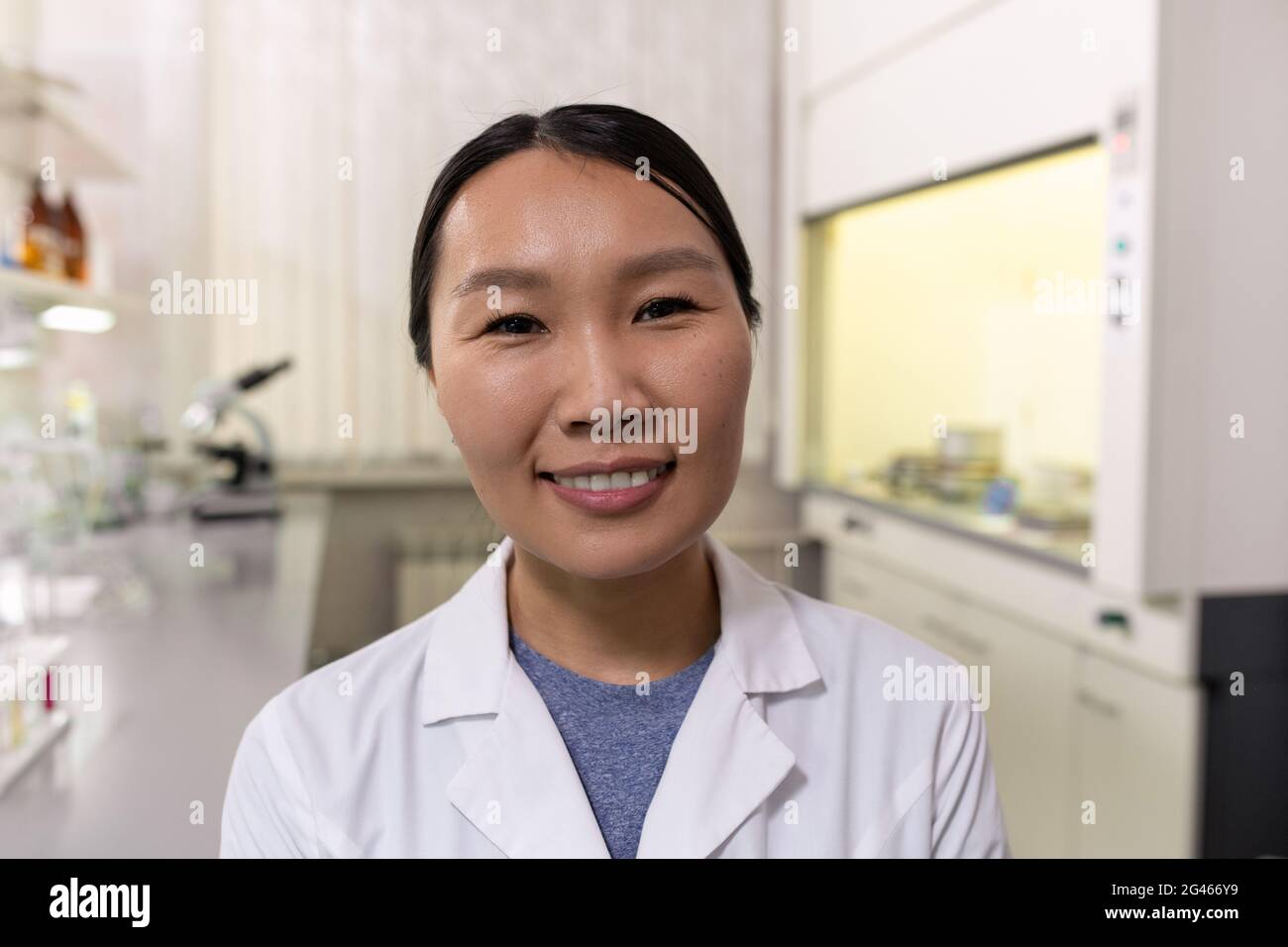 Giovane donna sorridente chimico di etnia asiatica in piedi in laboratorio Foto Stock