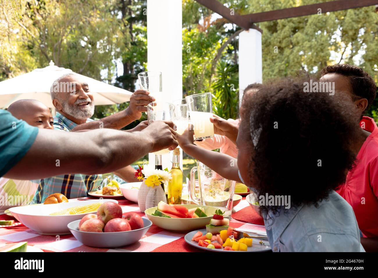 Coppia africana americana anziana e la loro famiglia seduti accanto ad un tavolo in giardino Foto Stock