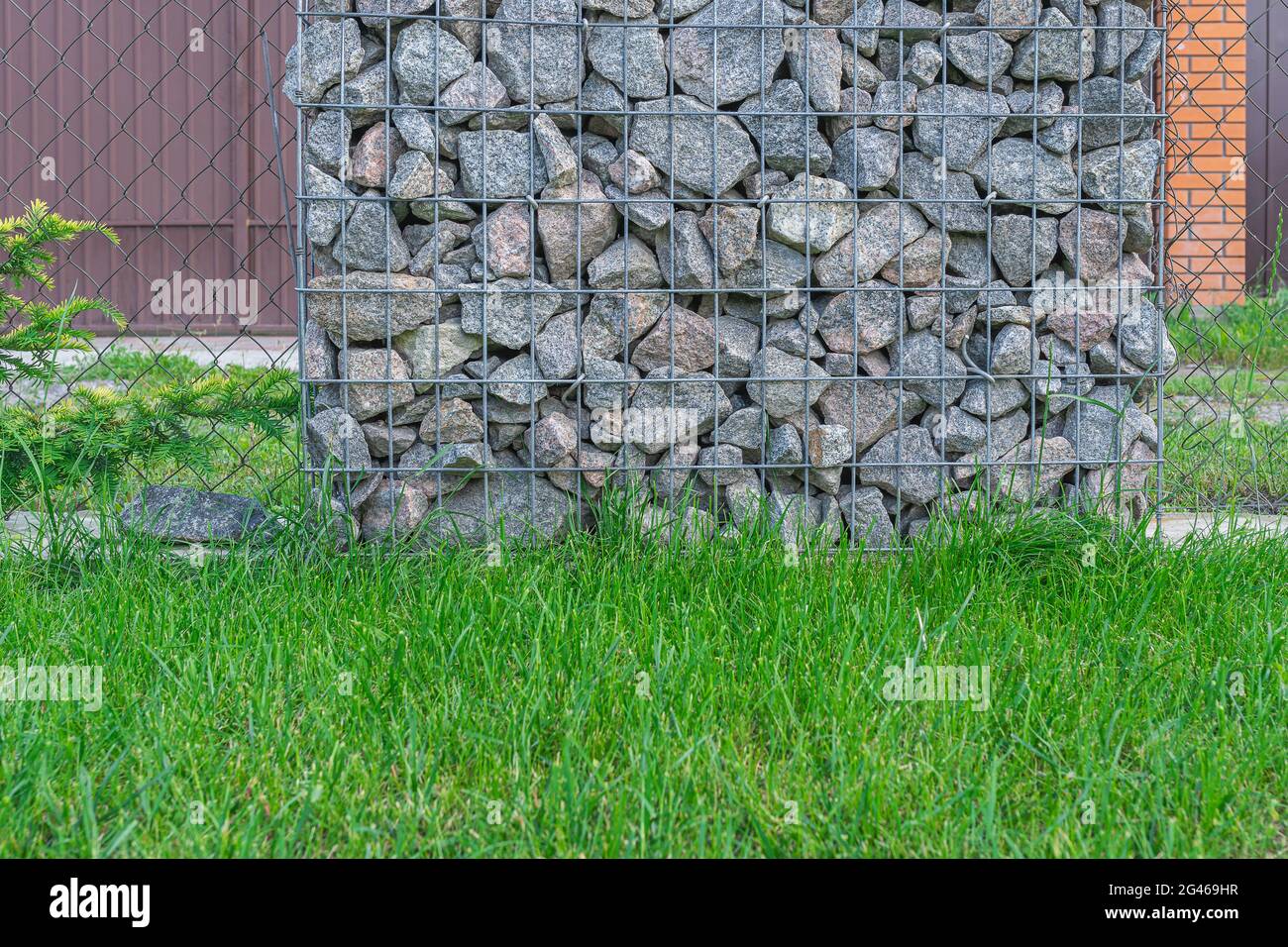 Gabbione wire mesh scherma con pietre naturali e pali di sostegno. Foto Stock