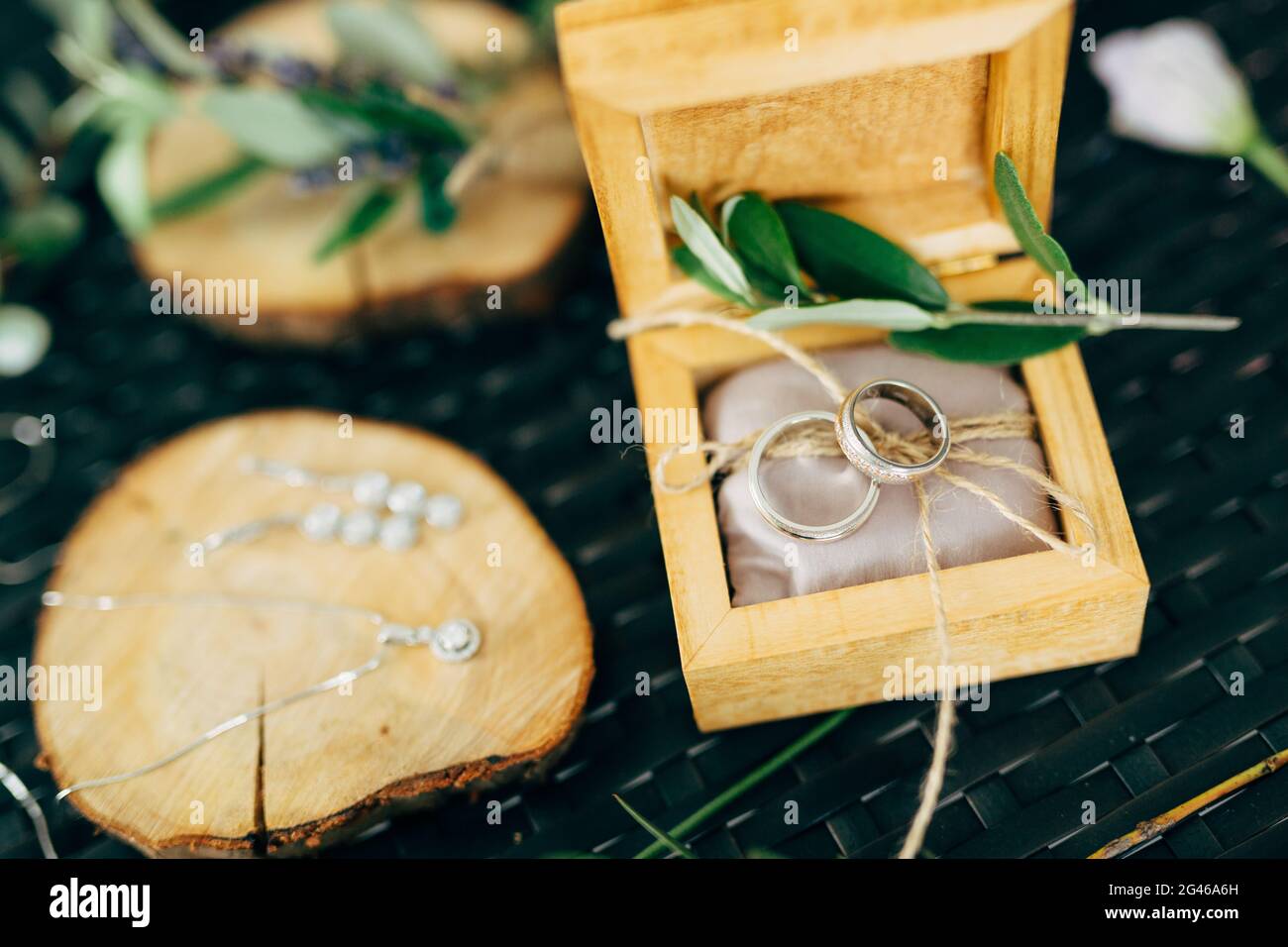 Scatola di legno aperta con anelli da sposa e un supporto in legno con orecchini e una catena con pendente. Foto Stock