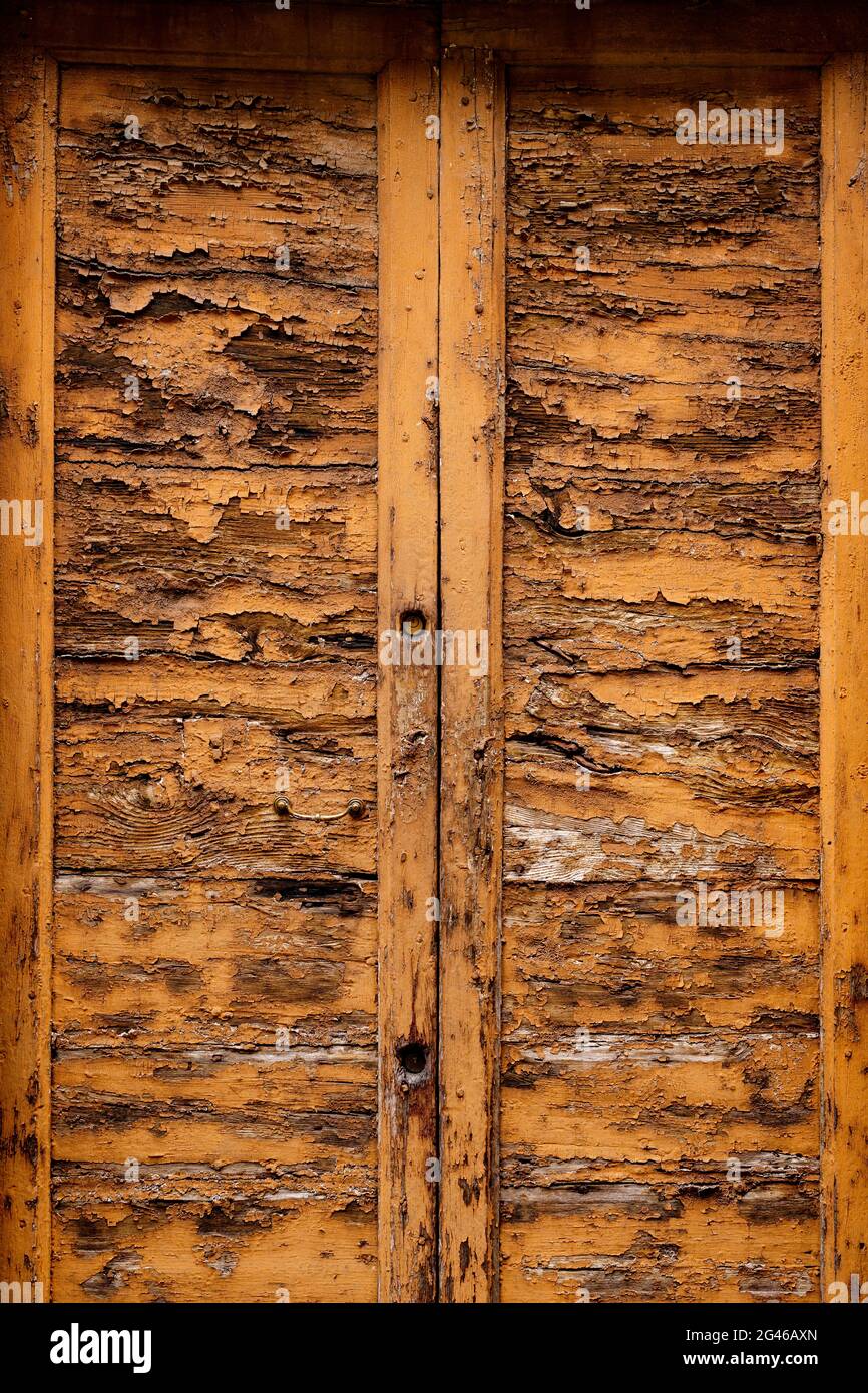 Un vecchio ingresso con doppio portone in metallo, sbucciato in legno Foto Stock