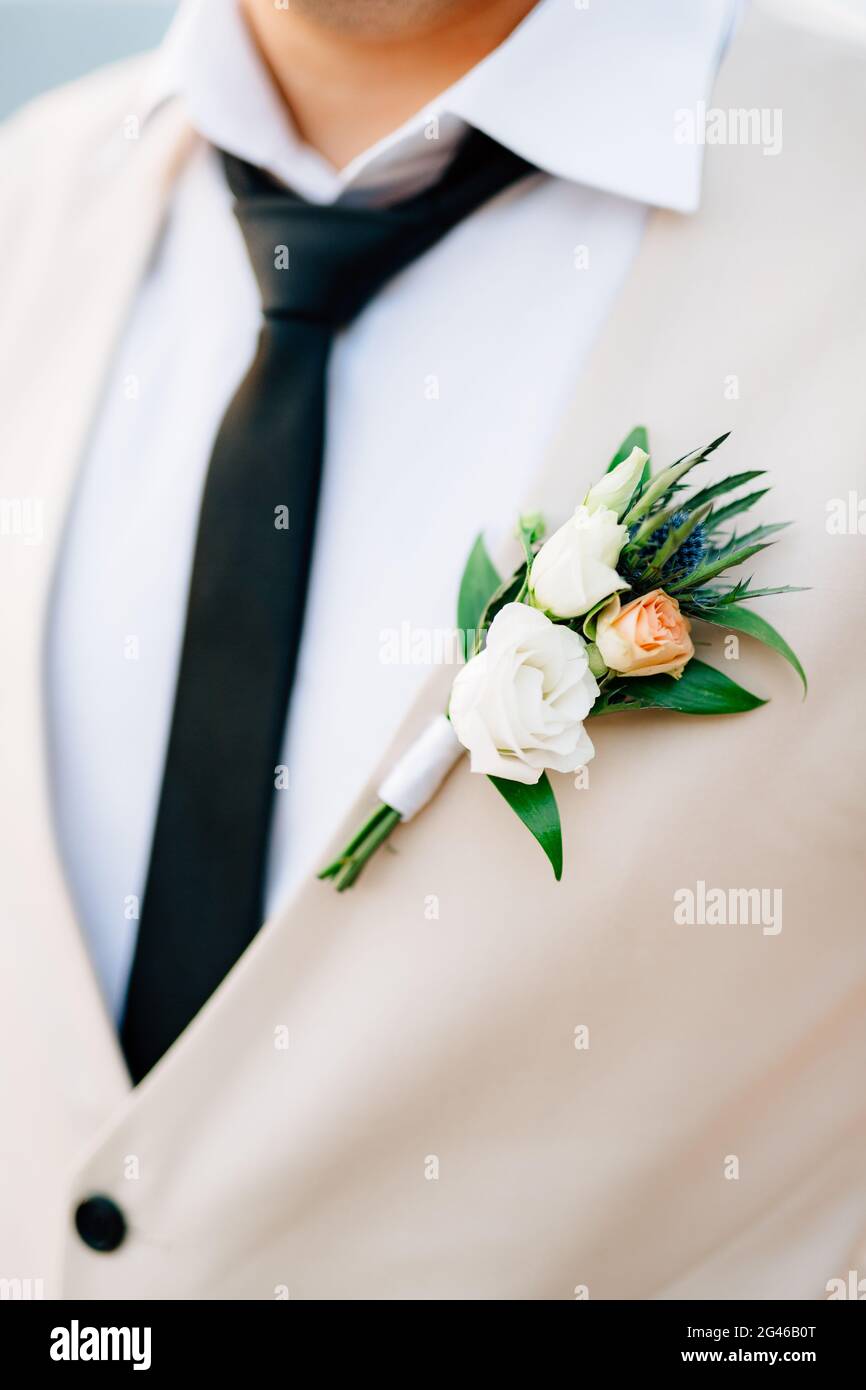 Camicia bianca, gilet con cravatta nera e boutonniere di rose e eryngium in primo piano sullo sposo Foto Stock