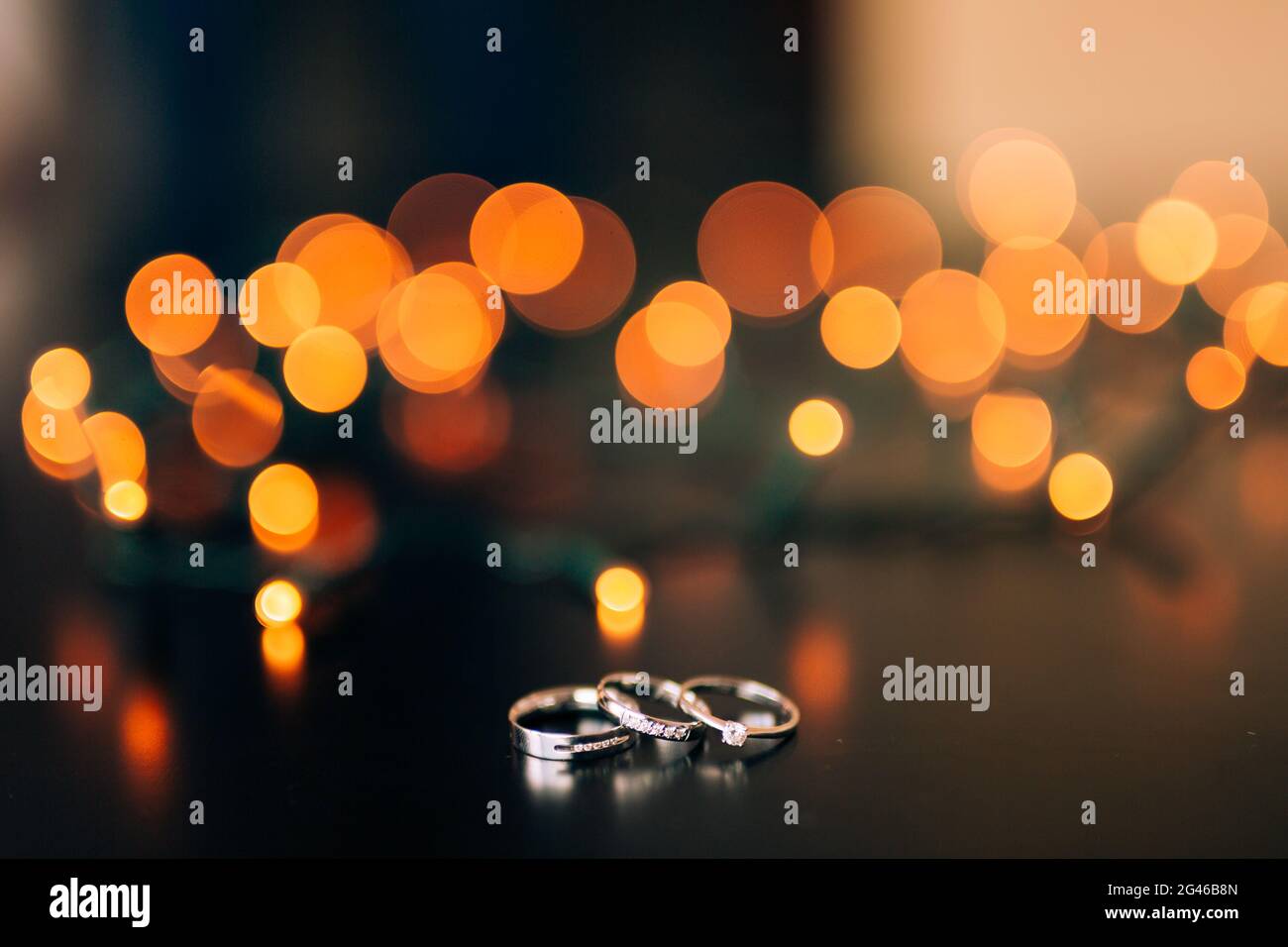 Gli anelli di nozze su sfondo giallo bokeh di ghirlande. Magica Foto Stock