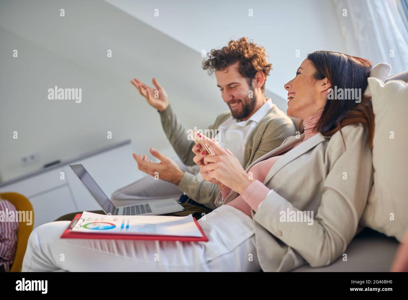 Una giovane coppia d'affari che si gode una bella conversazione sul divano in un'atmosfera rilassata in un appartamento dopo una dura giornata di lavoro. Affari, coppia, tempo libero, t Foto Stock