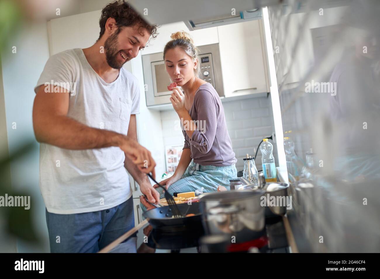 bella giovane coppia caucasica divertirsi in cucina. Beardy Guy fa colazione mentre la sua partner assaggia. Foto Stock