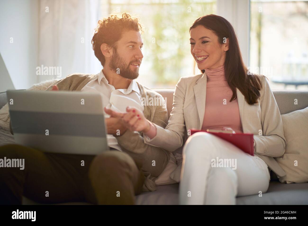 Giovane coppia d'affari allegra che si rilassa a letto godendo del contenuto del portatile in un lavoro da casa. Affari, persone, lavoro da casa Foto Stock
