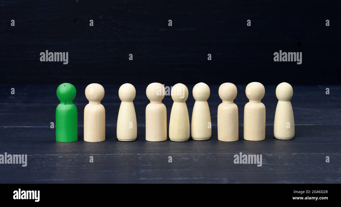 Figurina verde di un uomo tra la folla su sfondo blu. Il concetto di ricerca di dipendenti, persone di talento Foto Stock