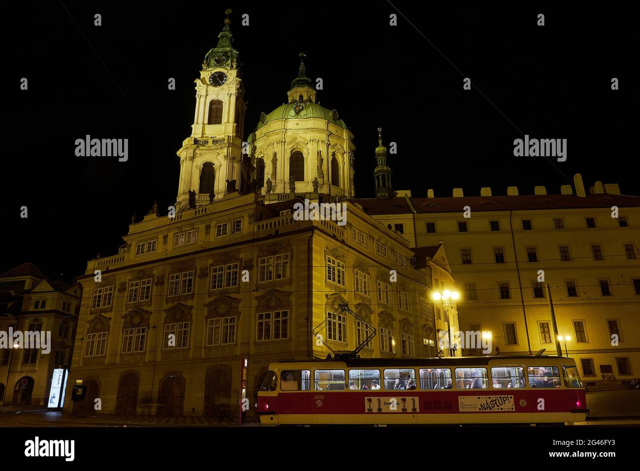Un tram con passeggeri davanti a una chiesa illuminata di San Nicola di notte, Praga, Repubblica Ceca Foto Stock