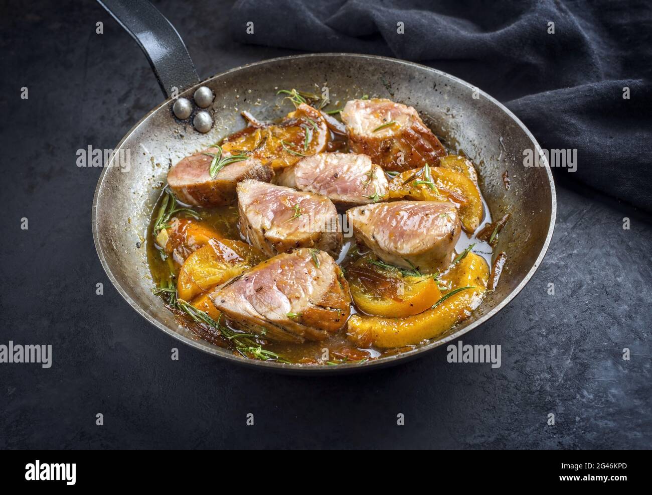 Tradizionali medaillons di filetto di maiale fritto con fette di arancia ed  erbe offerte come vista dall'alto in una padella rustica di ferro battuto  Foto stock - Alamy