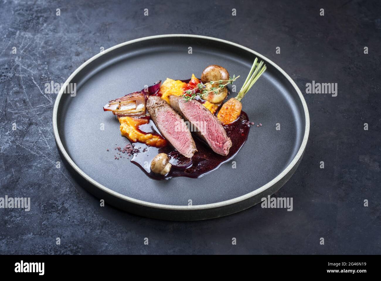 Filetto di lepre tradizionale in stile moderno brasato con frutti di bosco e jus di vino rosso con purea di carote e pota dolce Foto Stock