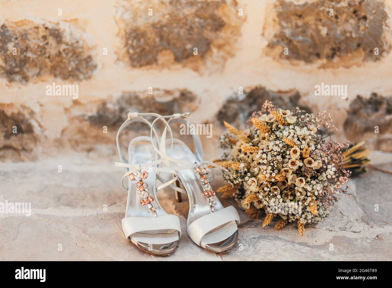 Scarpe di nozze di una sposa su un sfondo di pietra e di un bianco bouquet nuziale Foto Stock