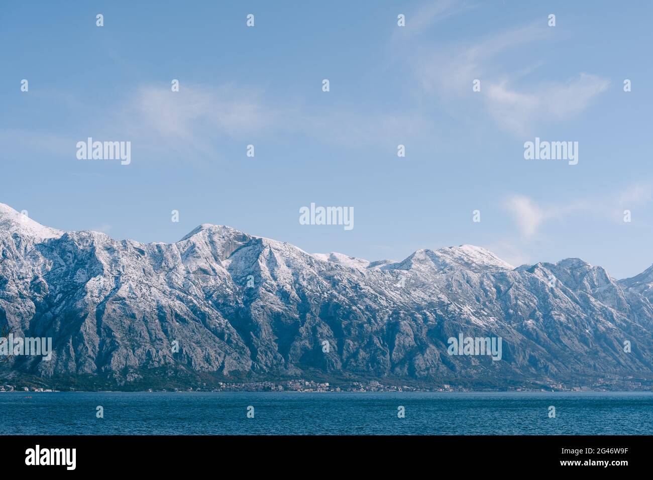 Cime innevate nella baia di Cattaro, Montenegro, sopra la città di Dobrota. Un'azienda agricola assitibile e di pesce in mare. Foto Stock