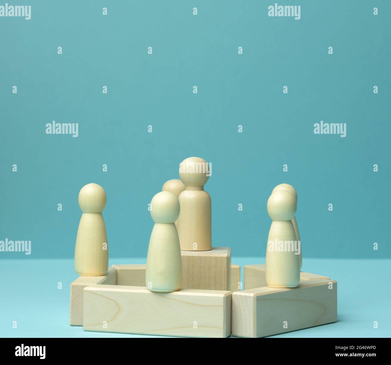 Figurine di legno di uomini su sfondo blu. Concetto di pubblico parlare, leadership e discussione Foto Stock