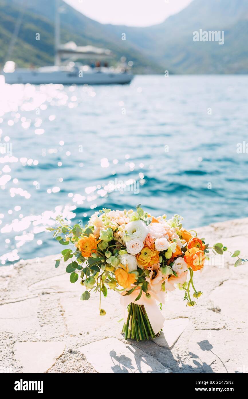 Bouquet nuziale di rose panna, rami di eucalipto, coppe di fiori gialli e arancioni, boccioli non fioriti di fiori bianchi e ri Foto Stock