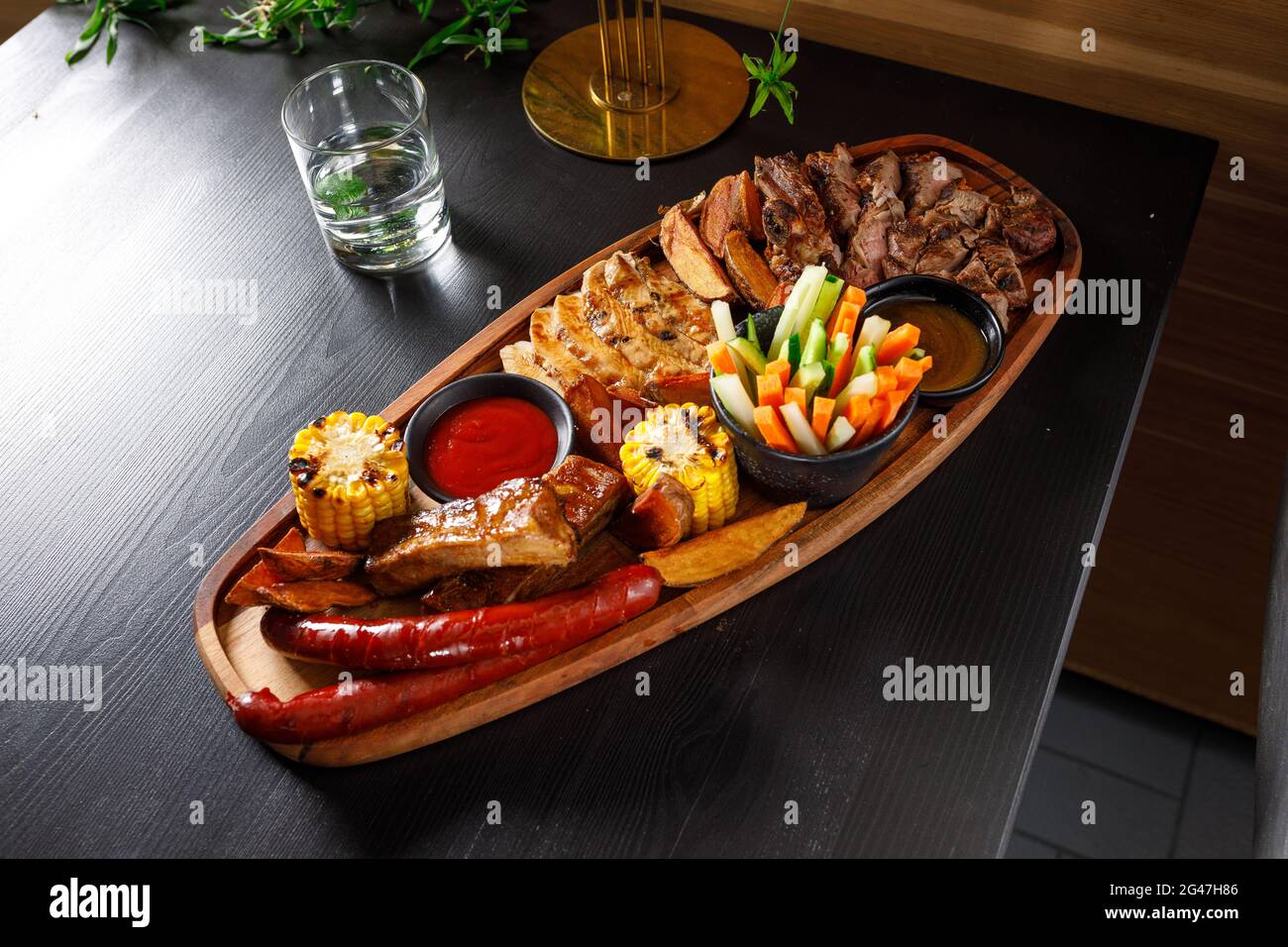 Set Josper di costolette di maiale, filetto di pollo, bistecca di ribeye, salsicce di caccia, mais, patate e verdure fresche Foto Stock