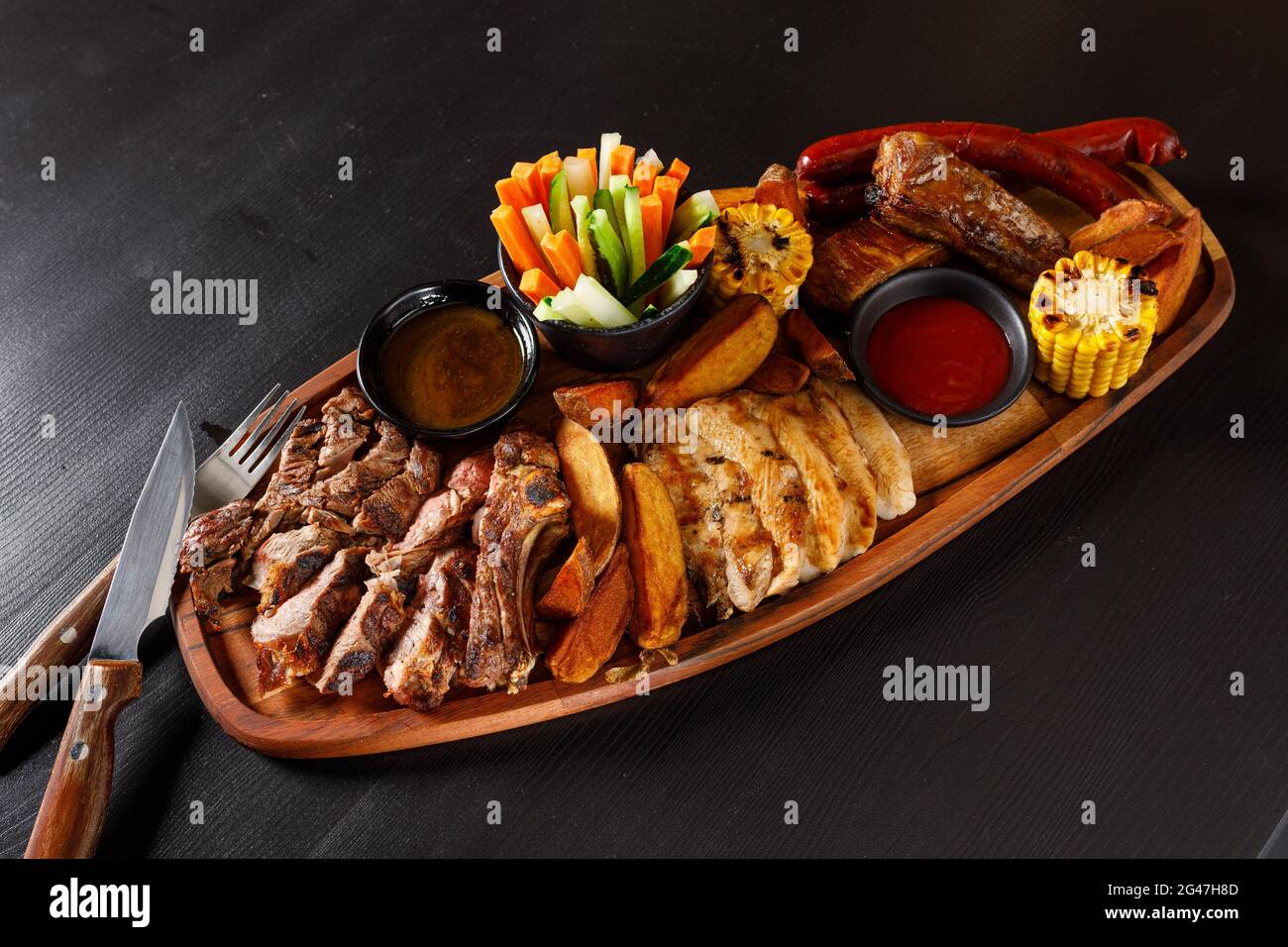 Set Josper di costolette di maiale, filetto di pollo, bistecca di ribeye, salsicce di caccia, mais, patate e verdure fresche Foto Stock