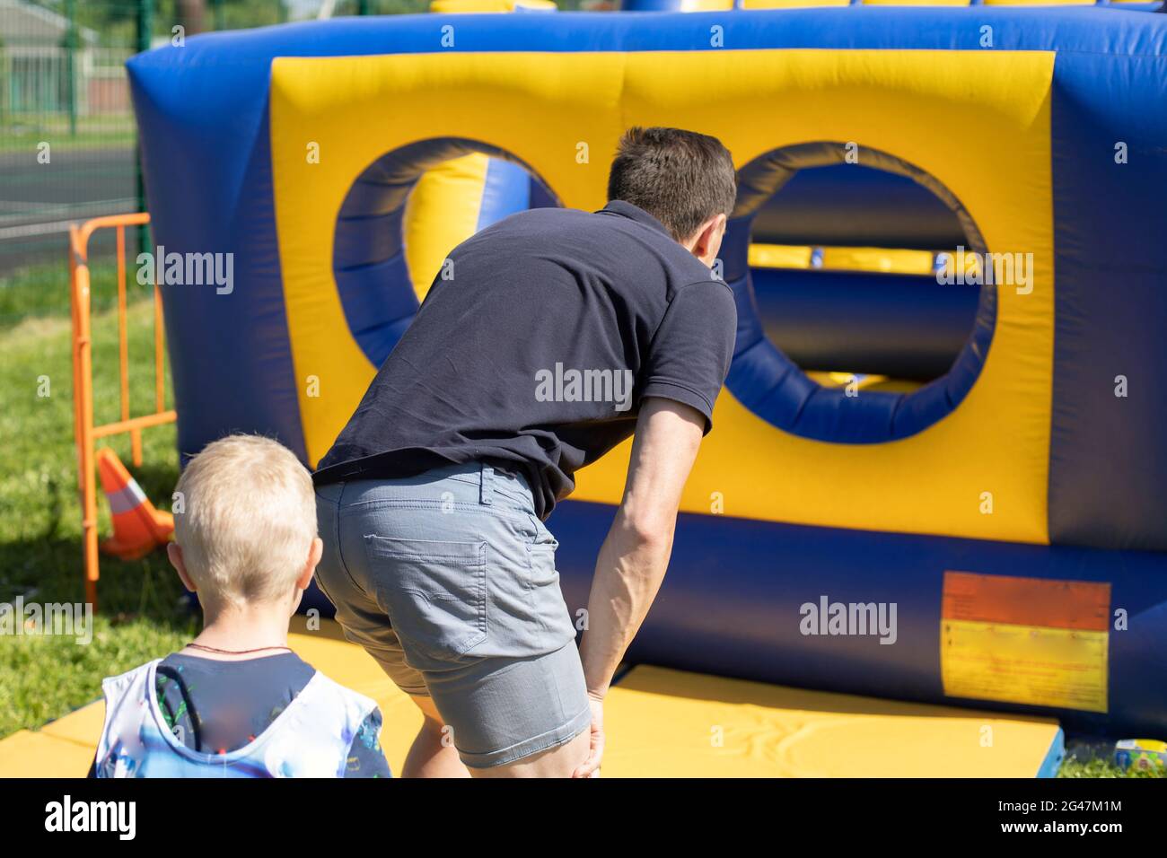 Un uomo corre all'interno di un ostacolo gonfiabile. Parco giochi gonfiabile. Vacanze attive in estate. Foto Stock