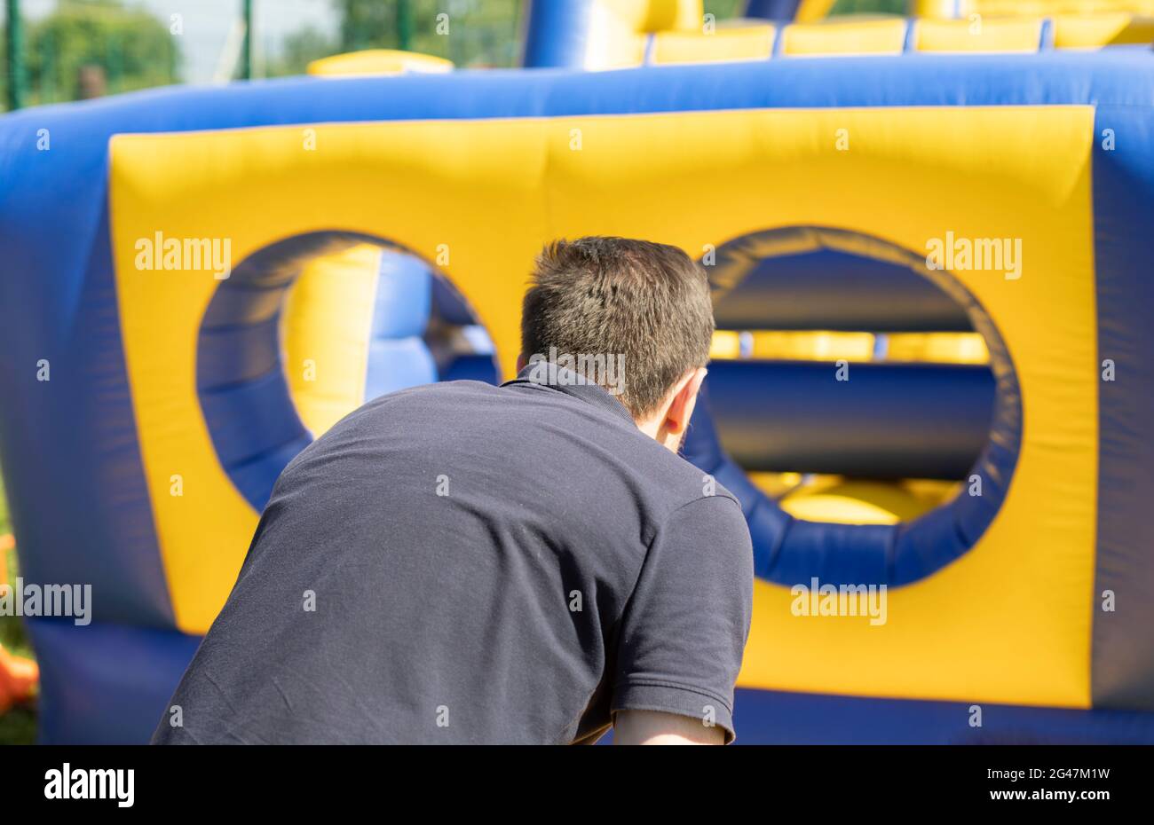 Un uomo corre all'interno di un ostacolo gonfiabile. Parco giochi gonfiabile. Vacanze attive in estate. Foto Stock