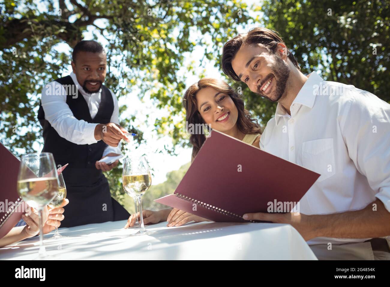 Amici che ordinano al cameriere Foto Stock