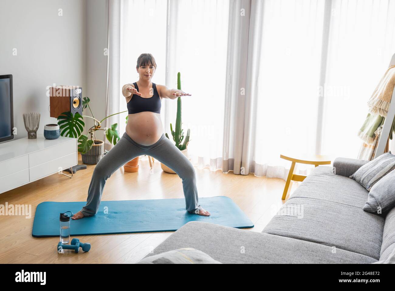 Donna incinta che fa esercizi a casa Foto Stock