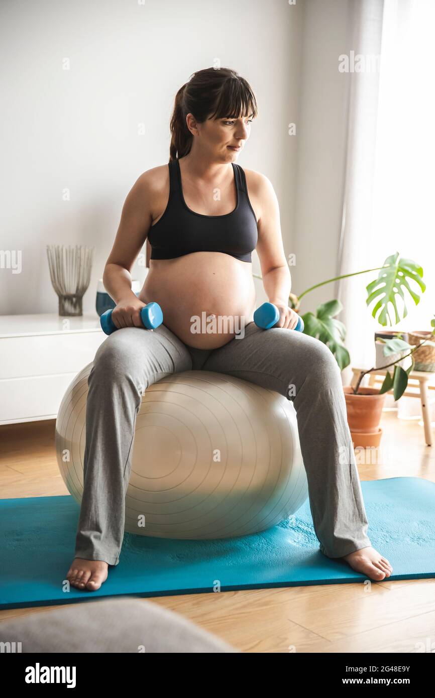 Donna incinta che fa esercizi a casa Foto Stock