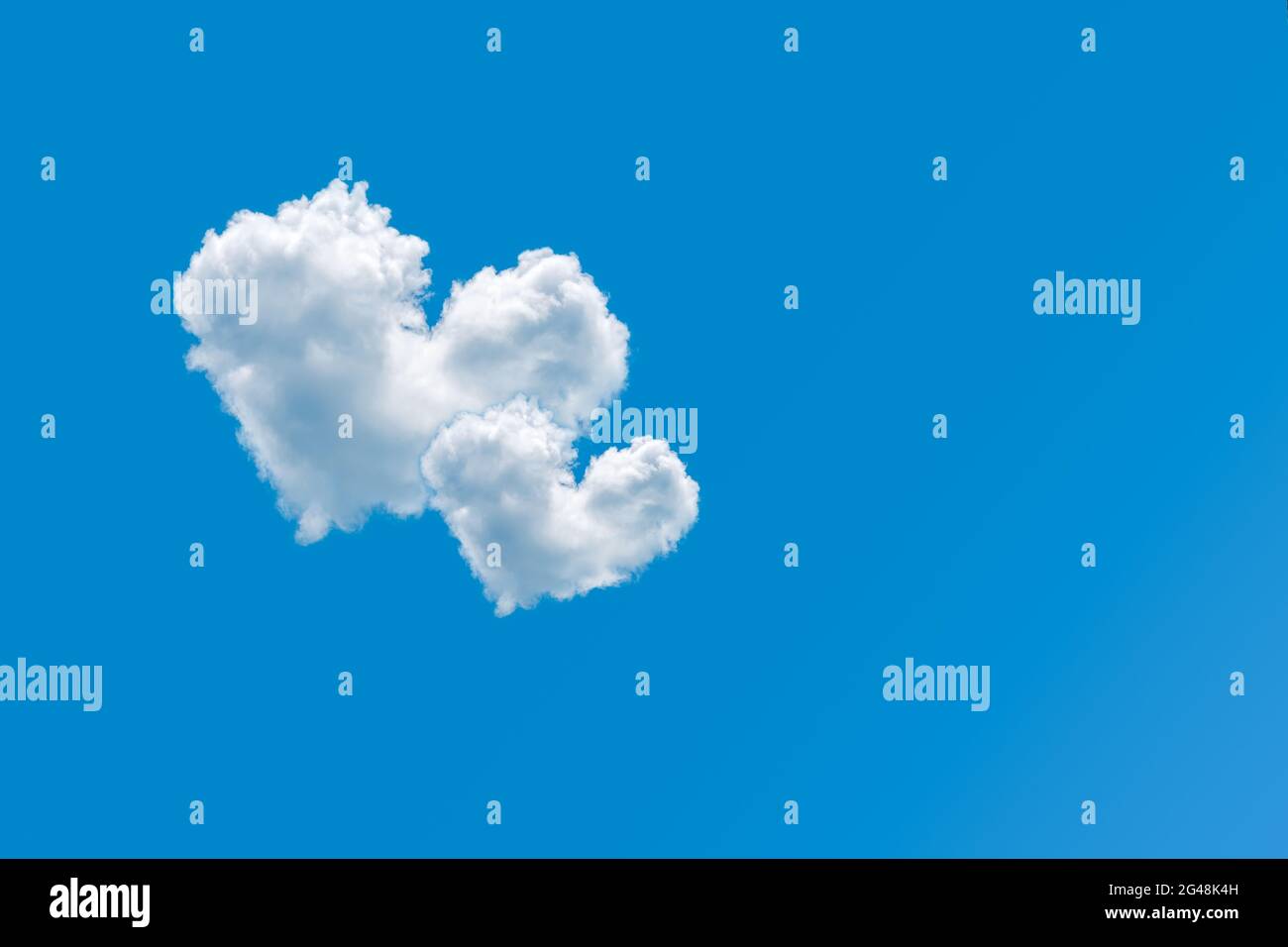 Coppia di nuvole a forma di cuore su uno sfondo blu chiaro del cielo. Concetto di amore e romanticismo. Coppia di cuori nuvolati nel cielo. Elemento di design per San Valentino Foto Stock