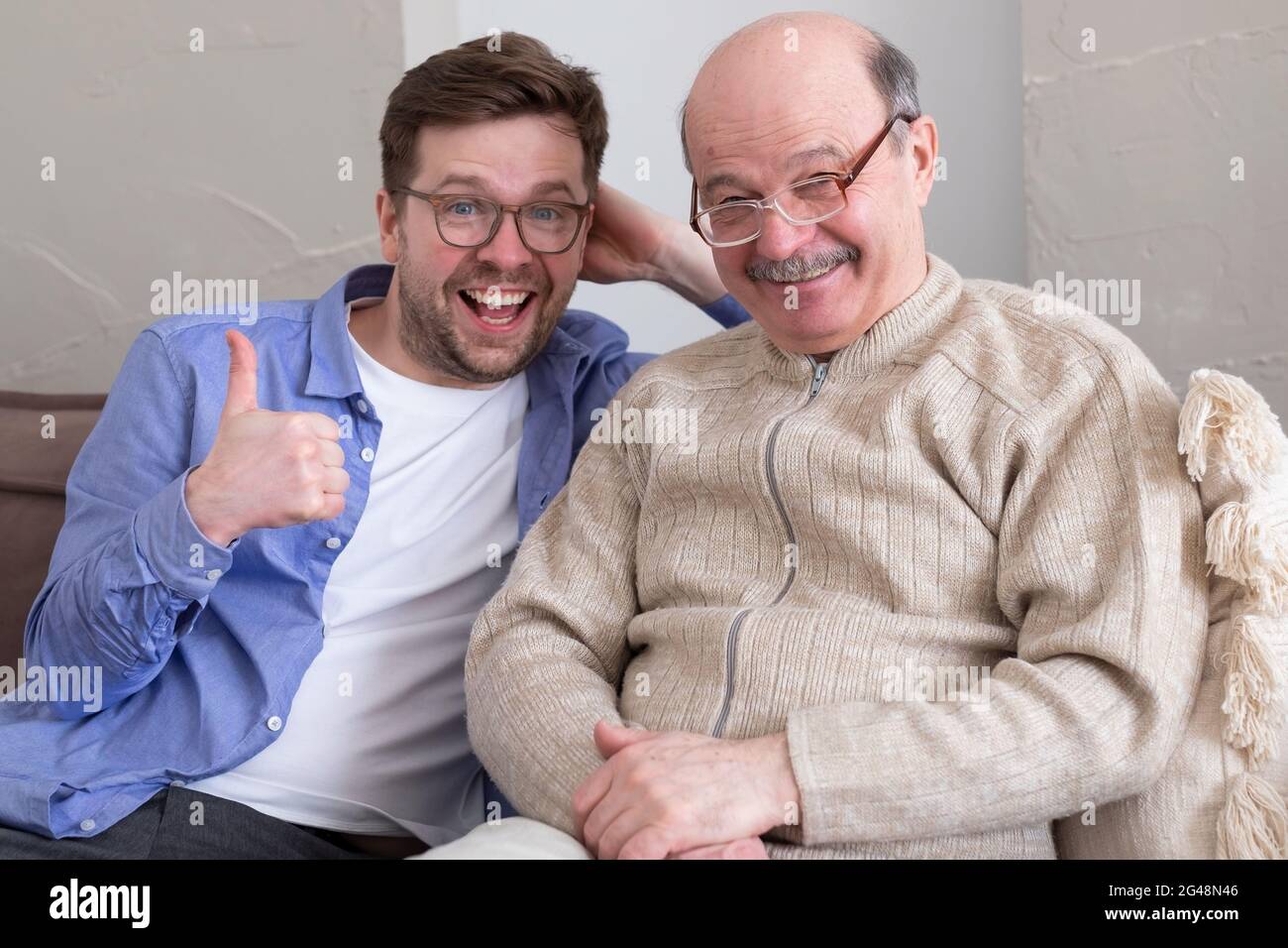 Ritratto closeup, famiglia, giovane uomo che tiene il pollice più vecchio manshowing in su Foto Stock
