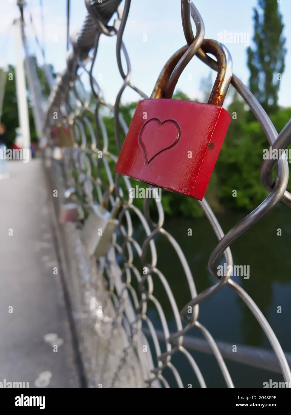 Immagine verticale di un lucchetto rosso con un cuore bloccato su una recinzione su un ponte Foto Stock