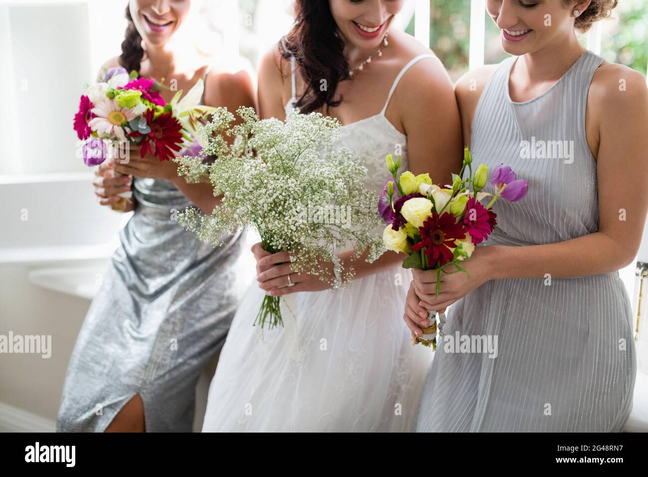 Sposa e bridesmaid in piedi con bouquet Foto Stock