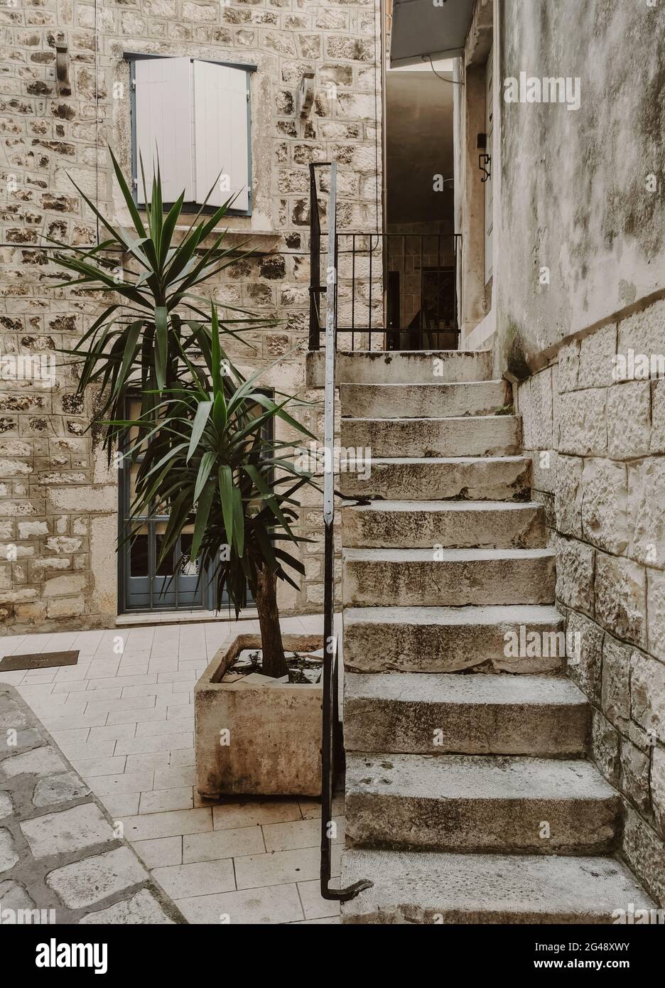 una taircase che porta alla porta d'ingresso della vecchia casa in pietra in una strada idilliaca della città vecchia. Foto Stock