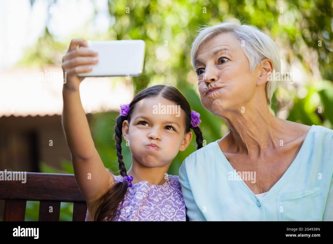 Ragazza e nonna che fanno i volti mentre prendendo selfie Foto Stock