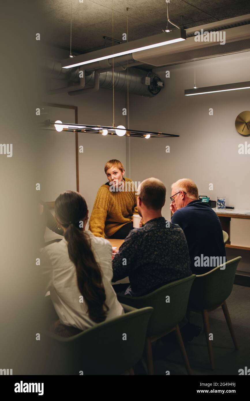 Imprenditore brainstorming progetto pianificazione con i colleghi in riunione. Donna seduta al tavolo e che parla con i colleghi di nuove idee di business. Foto Stock