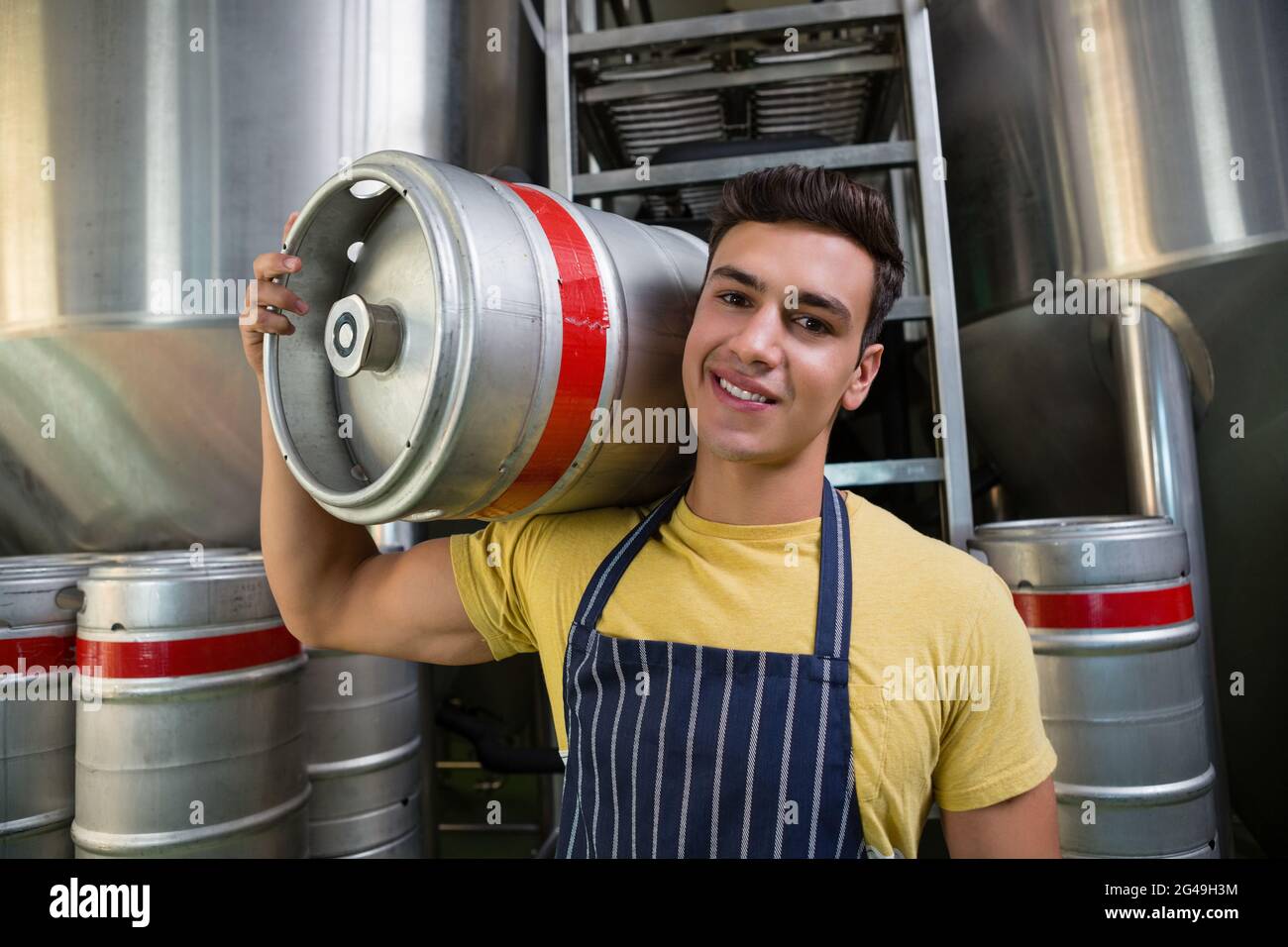 Ritratto di sorridente lavoratore che trasporta barile da serbatoi di stoccaggio Foto Stock