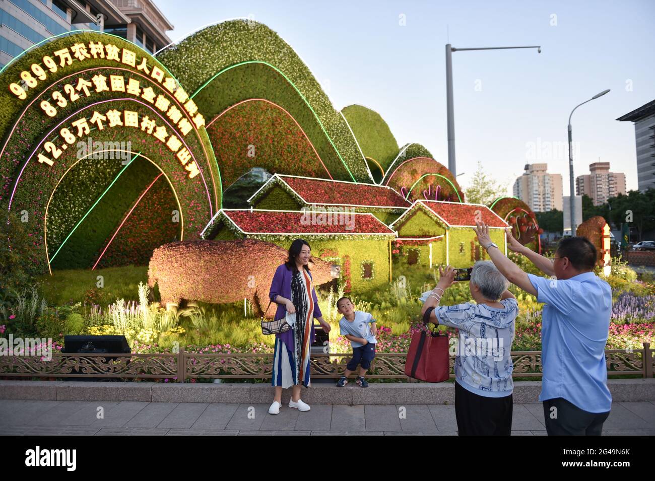 Pechino, Cina. 19 giugno 2021. La gente posa per le foto con le decorazioni dei fiori allestite lungo Chang'an Avenue a Pechino, capitale della Cina, 19 giugno 2021. Credit: Chen Zhonghao/Xinhua/Alamy Live News Foto Stock
