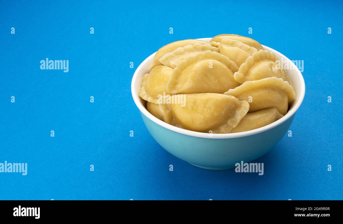 Gnocchi pieni, vareniki russo, pelmeni su sfondo blu Foto Stock