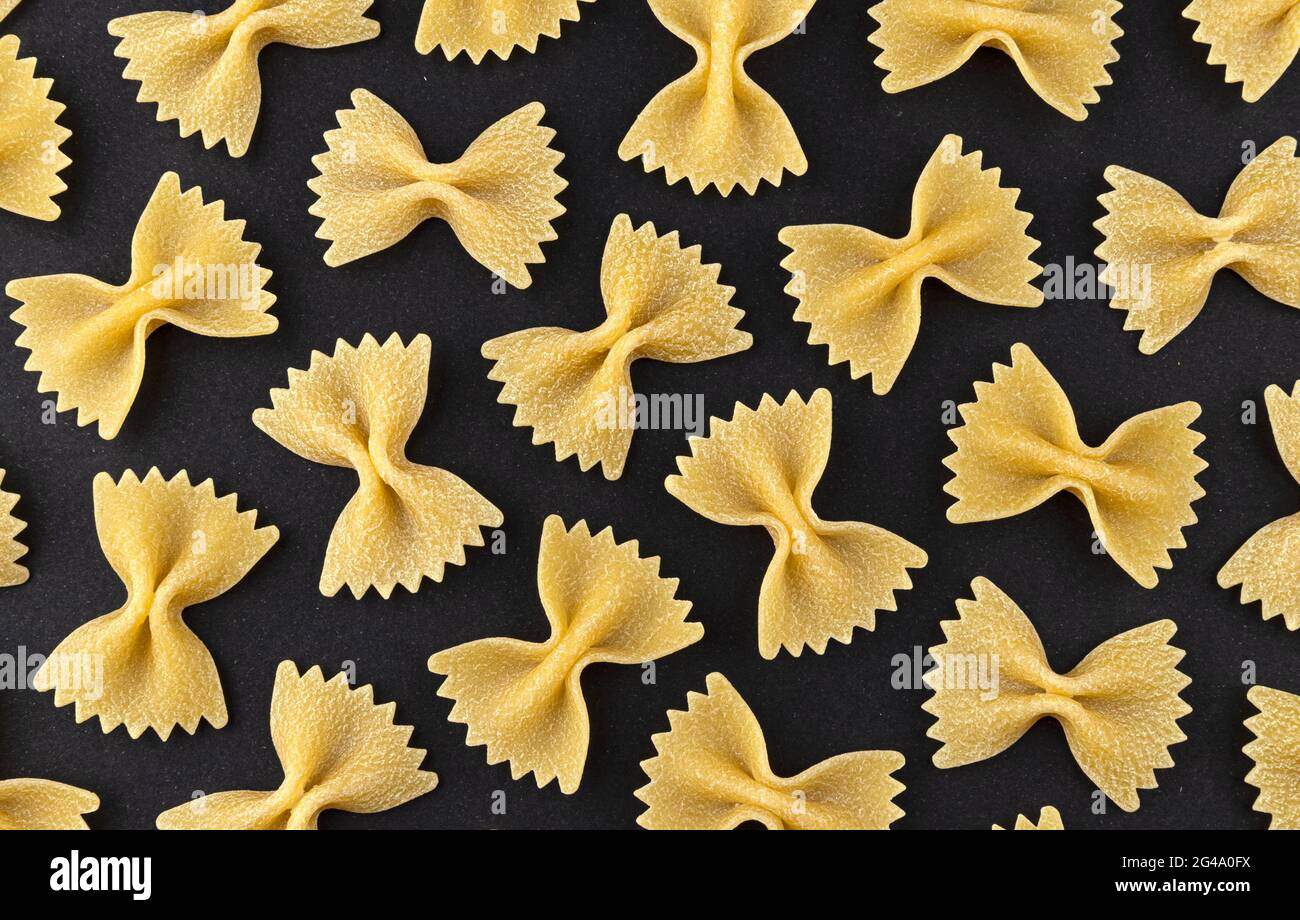 Motivo pasta FARFALLE su sfondo nero, vista dall'alto, struttura piatta Foto Stock