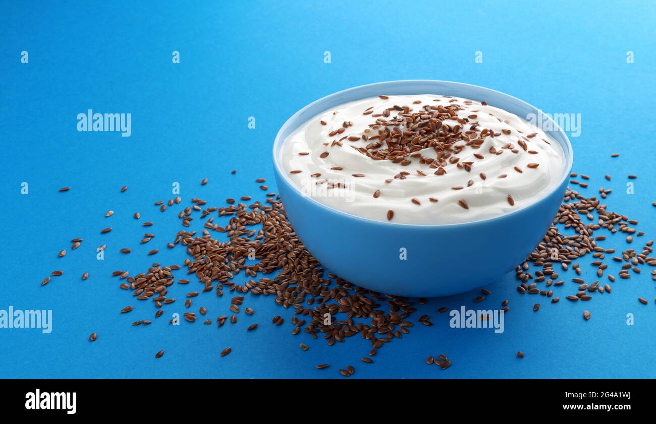 Yogurt con semi di lino isolato su sfondo blu Foto stock - Alamy