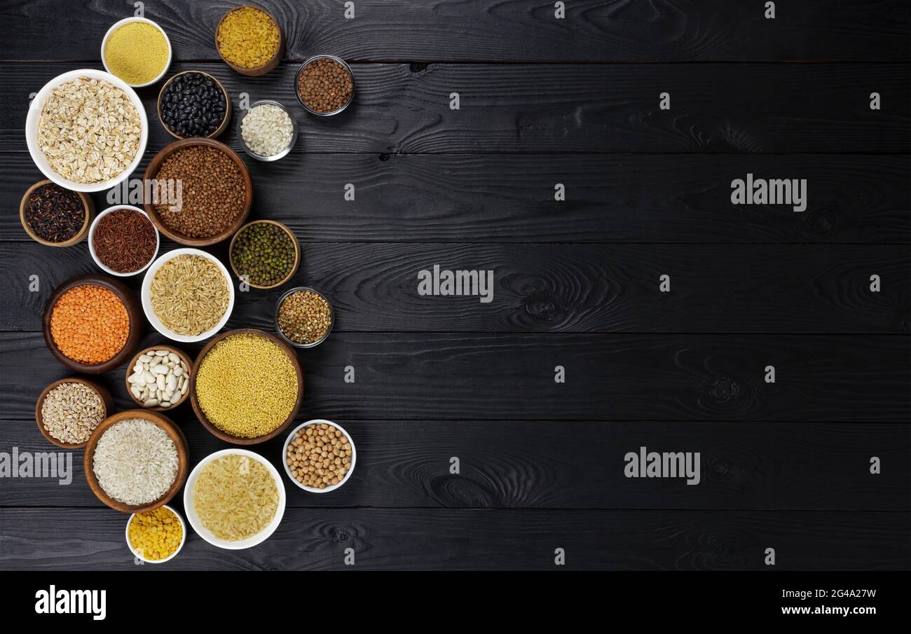 Cereali, granaglie, semi e semole e semolini di nero lo sfondo di legno Foto Stock