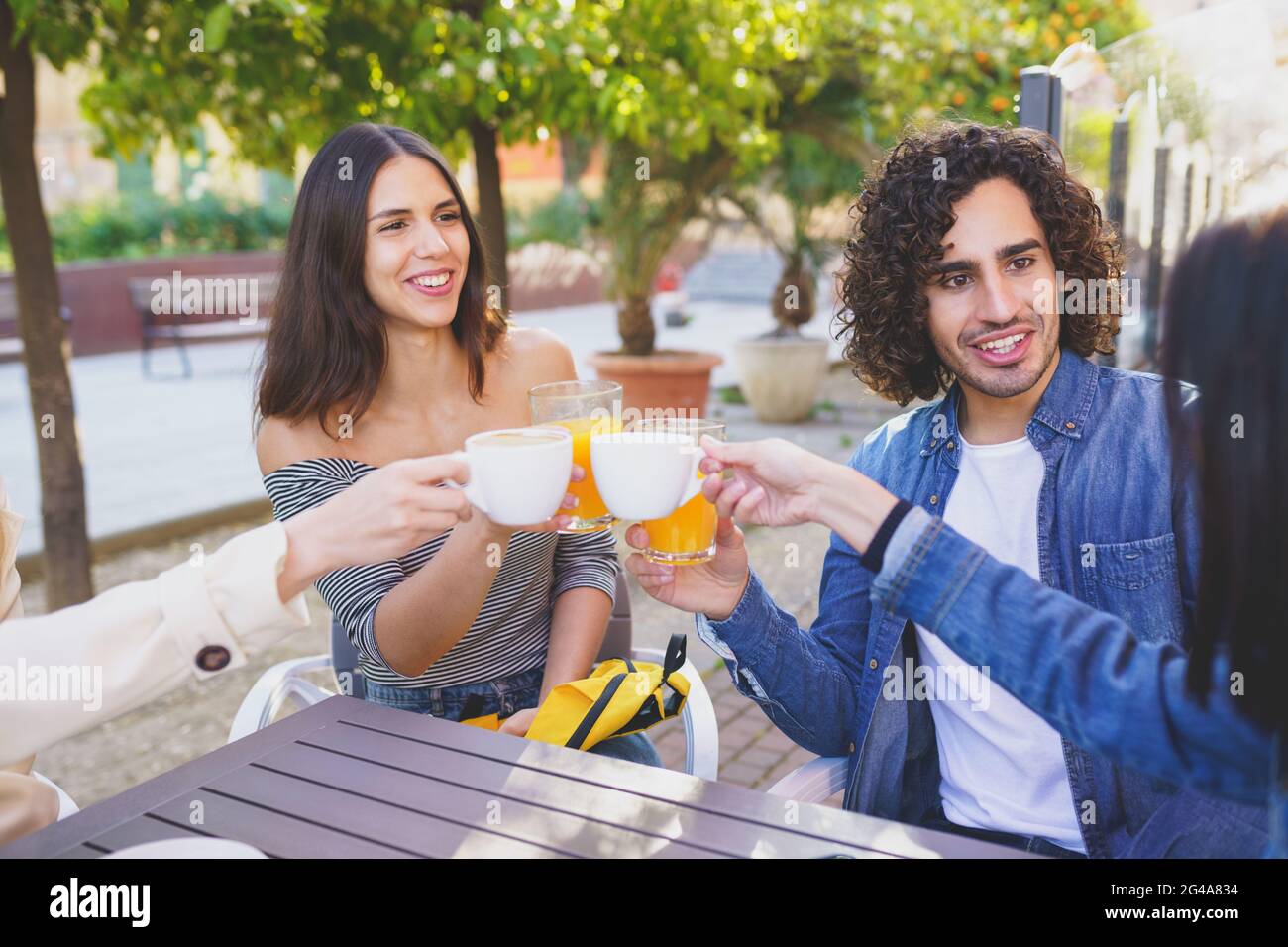 Gruppo multietnico di amici che brinda con le loro bevande mentre si beve insieme. Foto Stock