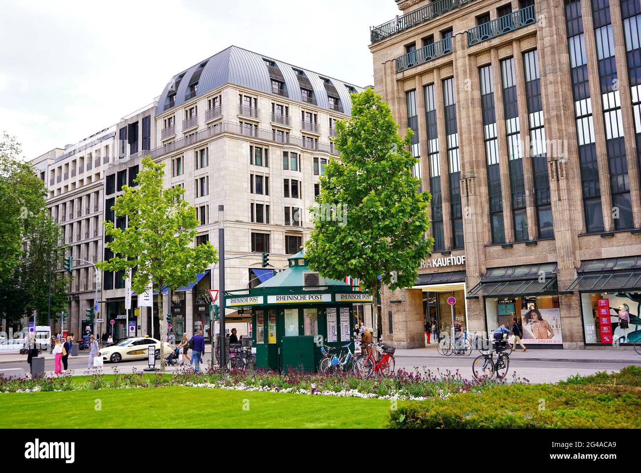 Scena cittadina nel centro di Düsseldorf, Germania. La storica Corneliusplatz con edicola d'epoca, hotel e grandi magazzini. Foto Stock