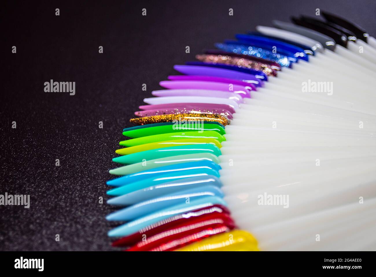 Esposizione di chiodi in gel verniciati con colori luminosi su sfondo scuro. Visualizzazione dei campioni di plastica per chiodi in gel. Servizio di bellezza Foto Stock