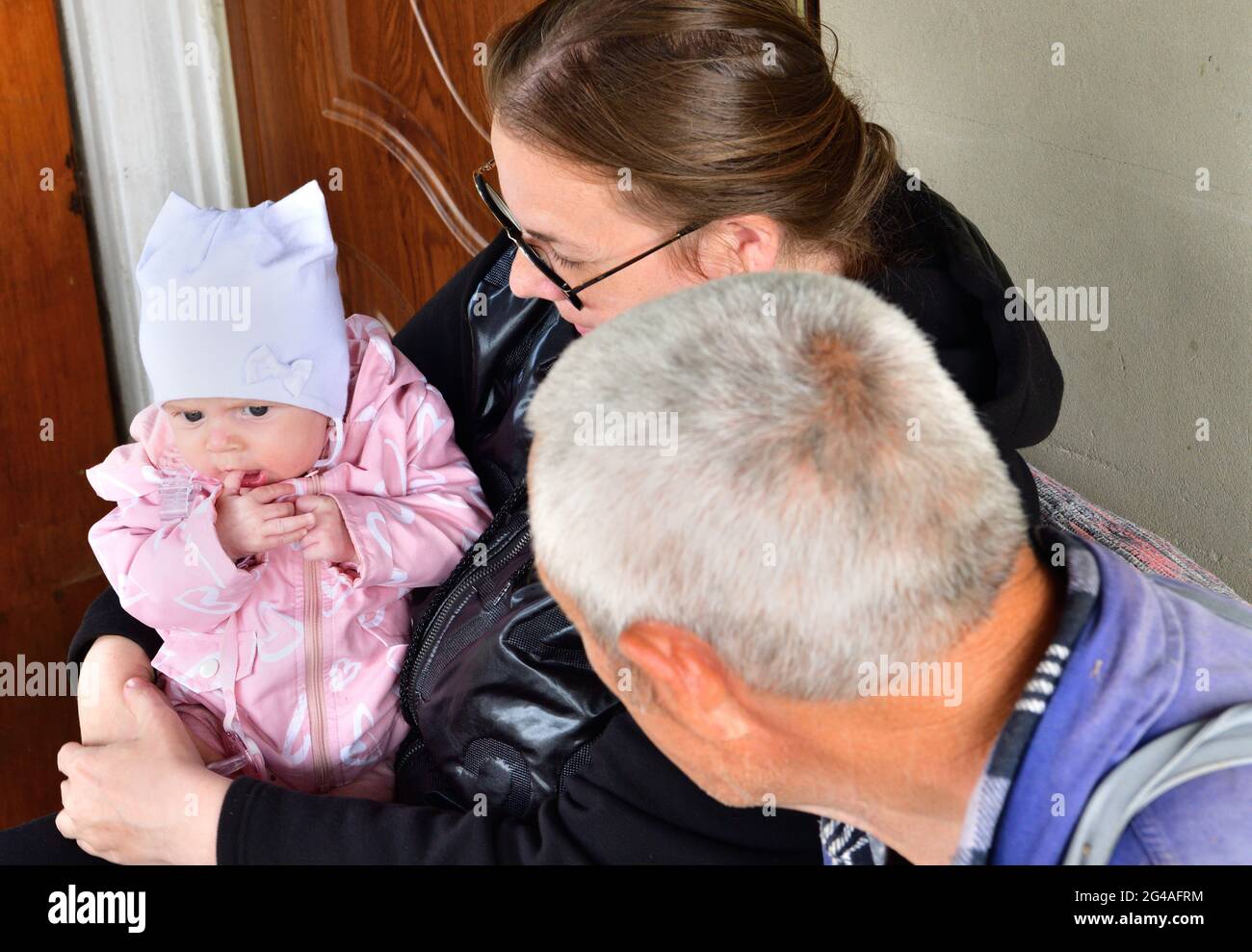 Nonno seduto in poltrona tenendo un neonato Foto stock - Alamy