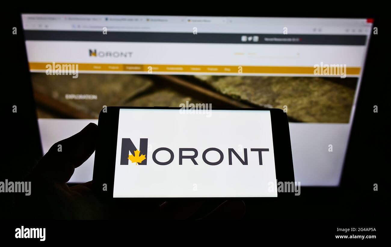 Persona che tiene il cellulare con il logo della società mineraria canadese Noront Resources Ltd. Sullo schermo di fronte alla pagina web aziendale. Mettere a fuoco il display del telefono. Foto Stock