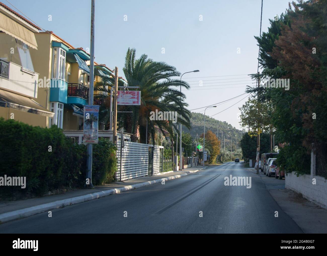 Una strada asfaltata in un villaggio, edifici e alberghi sul lato, bella montagna sullo sfondo, la natura a Thasos Foto Stock