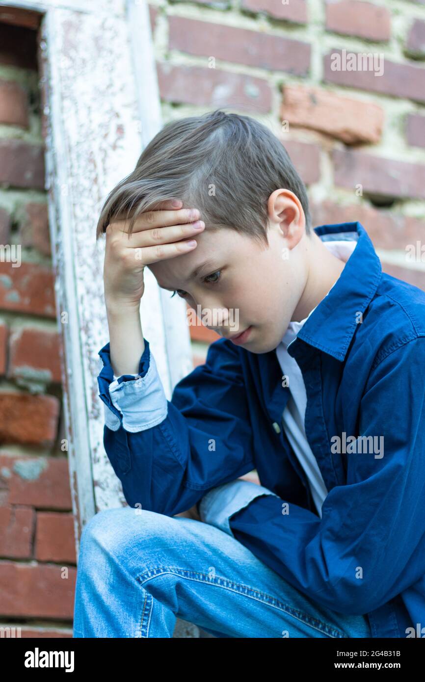 Un ragazzo vestito alla moda in una camicia blu si erge da una vecchia  porta stagionata contro un muro di mattoni. Primo piano. Messa a fuoco  selettiva. Verticale Foto stock - Alamy