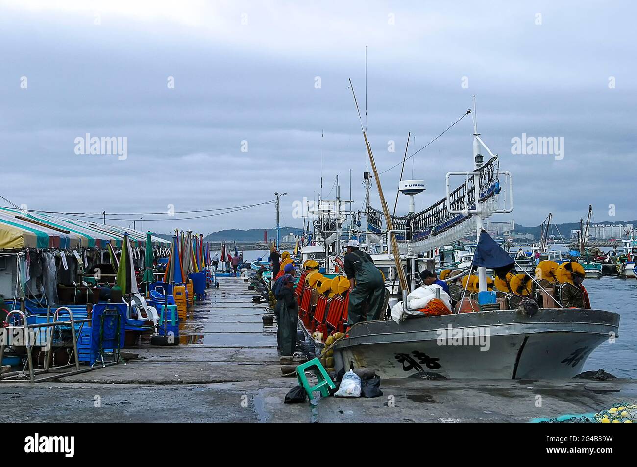 Giugno 20, 2021-Kosong, Corea del Sud-in questa foto scattata la data è il 13 giugno 2003. I pescatori che lavorano la mattina presto al porto di pesca nel porto di Keojin, Kosong, Corea del Sud. Kosong County nella provincia di Kangwon, Corea del Nord. Si trova nell'angolo più a sud-est della Corea del Nord, immediatamente a nord della zona demilitarizzata coreana. Prima della fine della guerra di Corea nel 1953, si è costituita una singola contea, insieme a quella che ora è la contea sudcoreana con lo stesso nome. In una successiva riorganizzazione, la contea assorbì la parte meridionale della contea di Tongchon. Foto Stock