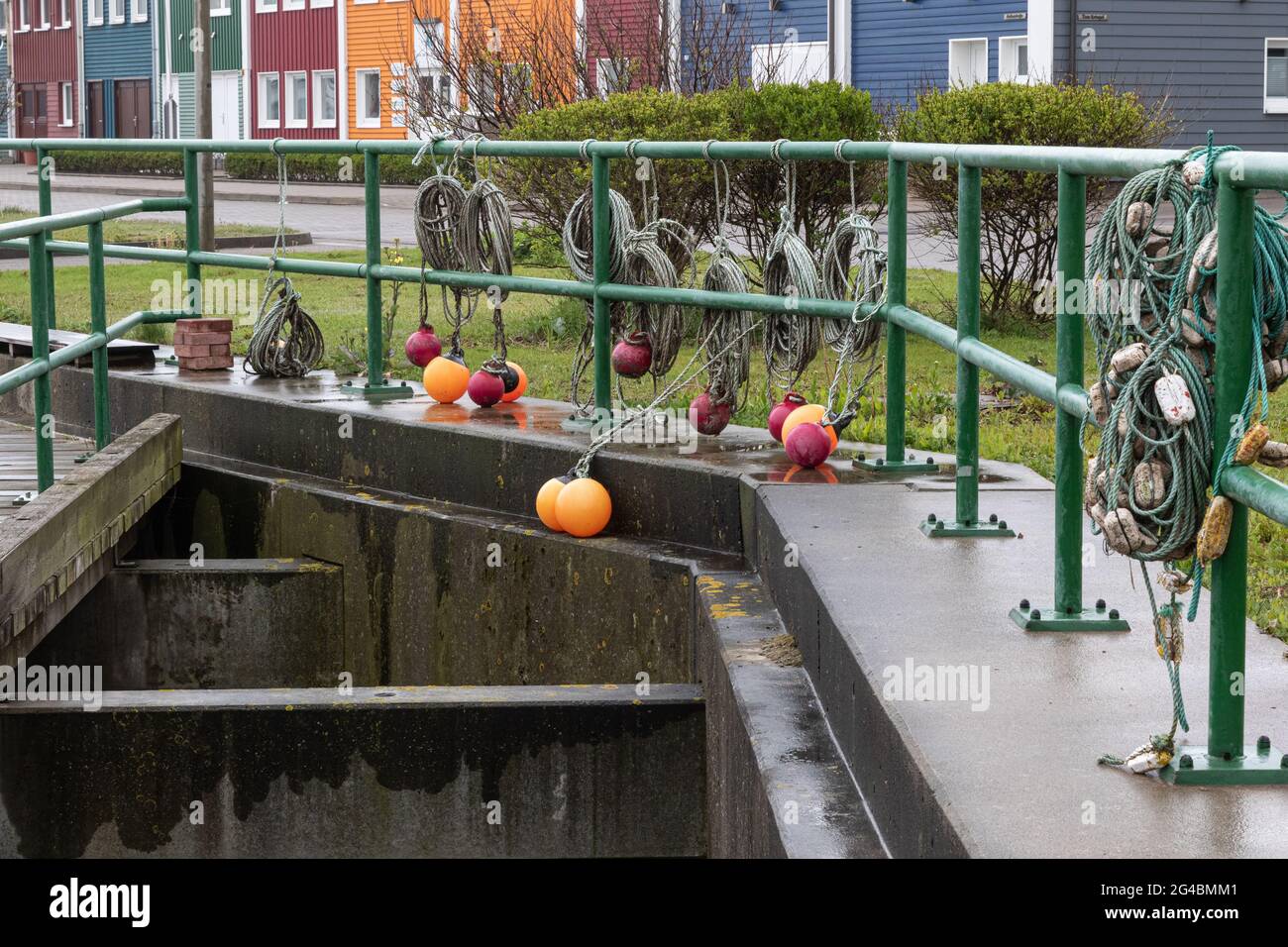 Le boe rotonde in arancione e rosso scuro e le funi a spirale appendono sulla ringhiera verde. Foto Stock