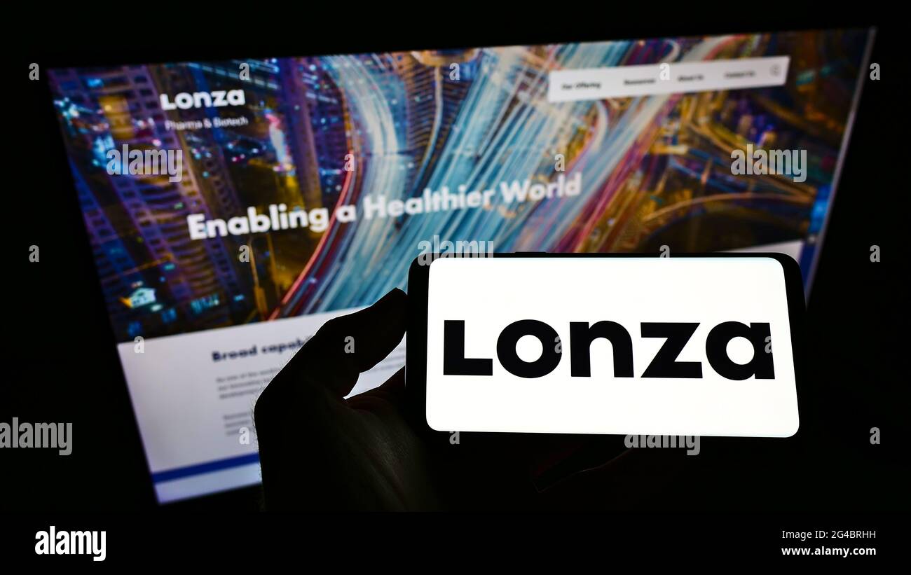 Persona titolare smartphone con logo della società chimica svizzera Lonza Group AG sullo schermo davanti al sito web. Mettere a fuoco il display del telefono. Foto Stock Persona titolare smartphone con logo della società chimica svizzera Lonza Group AG sullo schermo davanti al sito web. Mettere a fuoco il display del telefono. Foto Stock